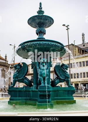 Vista frontale della storica fontana in bronzo Fonte dos Leões con leoni alati che spruzzano acqua in Praça Gomes Teixeira a Porto, Portogallo Foto Stock