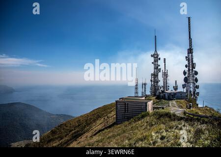 Vista ad alto angolo delle antenne di comunicazione e delle torri radio sulla cresta sommitale del Monte fasce, affacciata sul blu del Mar Ligure nei pressi di Genova. Foto Stock