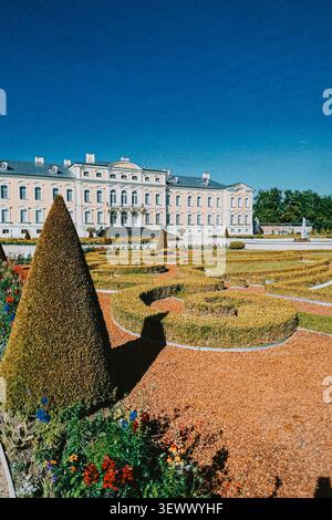 Rundale, Lettonia - 26 giugno 2026: Elegante palazzo barocco che si affaccia su un giardino formale meticolosamente progettato con siepi geometriche e aiuole colorate Foto Stock