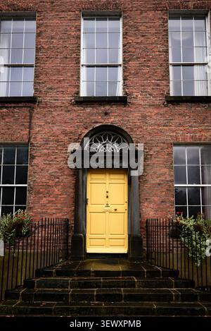 Porta gialla in stile georgiano su una casa storica in mattoni rossi a Kilkenny, Irlanda Foto Stock