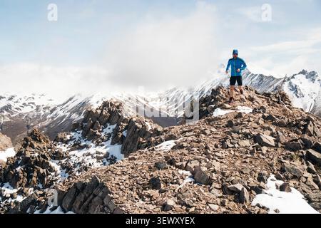 Atleta maschile che corre su un crinale innevato Foto Stock
