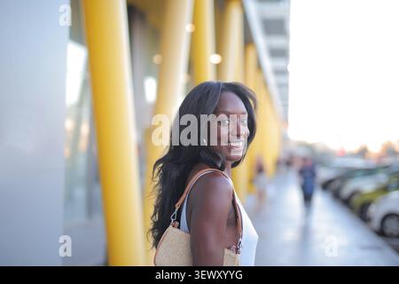 Giovane donna nera sorridente sulla spalla all'aperto Foto Stock