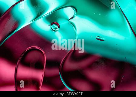 Vista macro dello sfondo verde neon lucido e delle onde liquide magenta Foto Stock