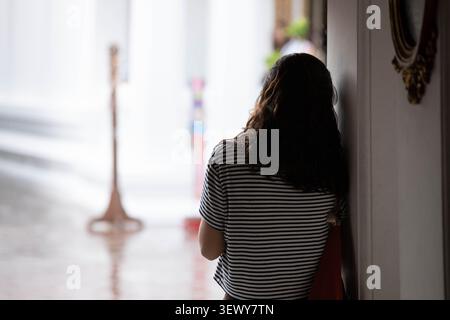 Donna in piedi e appoggiata al montante, vista posteriore. Foto Stock