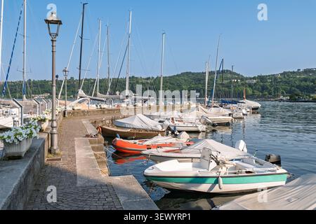 Piccoli motoscafi e barche a vela ormeggiati lungo una passeggiata sul lungomare in una tranquilla giornata estiva. Tranquillo scenario turistico e concetto di destinazione di viaggio. Foto Stock