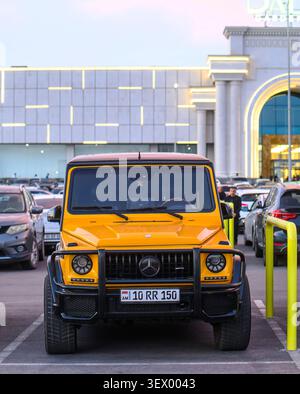Veicolo giallo fuoristrada Mercedes-Benz Classe G parcheggiato di fronte a un edificio moderno. L'auto ha un design robusto e un paraurti protettivo Foto Stock