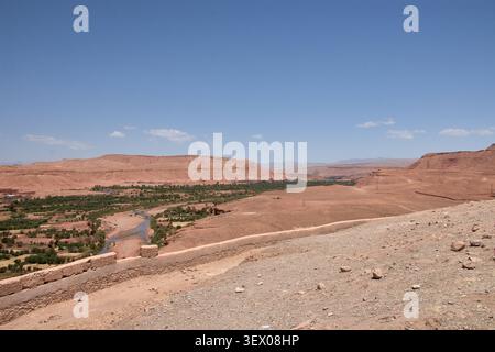 Il vasto e arido orizzonte desertico che circonda la provincia di Ouarzazate, in Marocco, si estende maestosamente sotto un cielo blu punteggiato di nuvole mostruose, Re Foto Stock