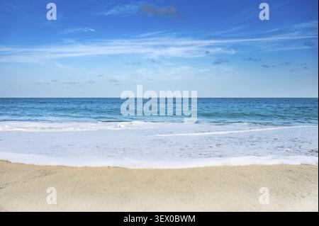 Un bellissimo oceano blu con una linea di schiuma bianca. Il cielo è limpido e il sole splende Foto Stock