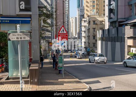 Happy Valley, quartiere di Hong Kong. Incrocio tra Mui Hing Street e Sing Woo Road, riducete la velocità ora cartello stradale Foto Stock