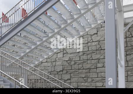 Una vista affascinante di una scala a chiocciola in un edificio moderno, che mostra eleganti ringhiere in legno e pareti in marmo. Questa fotografia architettonica è i Foto Stock