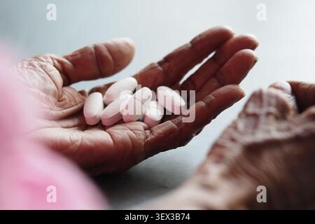donna anziana che tiene le compresse in mano durante la routine quotidiana Foto Stock