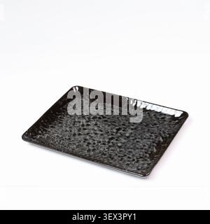 Piatto ceramico rettangolare nero testurizzato vuoto su sfondo bianco, vista ad angolo alto Foto Stock