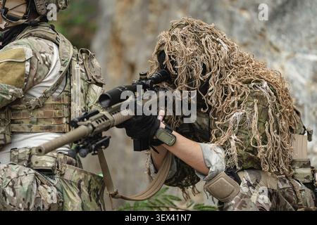 Tiratore militare STATUNITENSE in tuta mimetica ghillie che conduce operazioni di precisione di cecchino, missione di ricognizione tattica avanzata, obiettivo a lungo raggio OBS Foto Stock