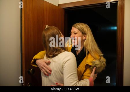 Due amici condividono un caldo abbraccio a una porta aperta, scambiandosi i saluti Foto Stock