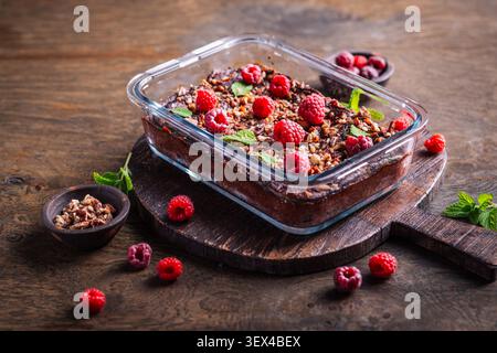 Decadente brownie al lampone al cioccolato cotto in piatto di vetro, condito con noci e menta Foto Stock