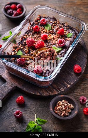 Decadente brownie al lampone al cioccolato cotto in piatto di vetro, condito con noci e menta Foto Stock