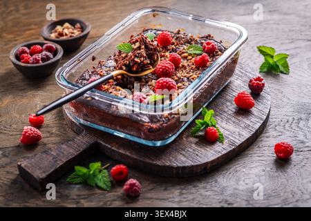 Decadente brownie al lampone al cioccolato cotto in piatto di vetro, condito con noci e menta Foto Stock