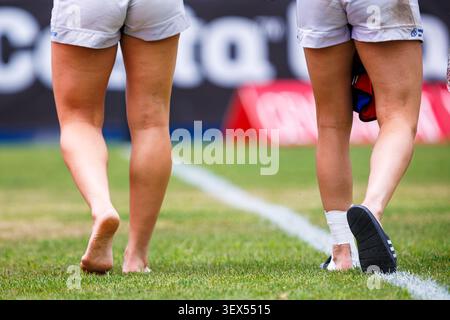 Villajoyosa,Alicante,Spagna.06-20-2026.Un'inquadratura dettagliata e ad angolo basso che si concentra sulle gambe e sui piedi di due giocatrici di rugby che camminano sul tappeto erboso, Foto Stock