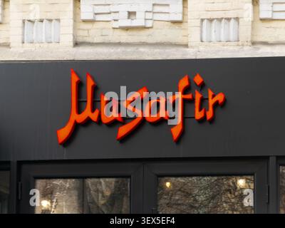 Kiev, Ucraina - 21 marzo 2026: Cartellonistica Musafir con lettere rosse stilizzate su uno sfondo nero sopra una porta d'ingresso di vetro in una trafficata metropolita Foto Stock