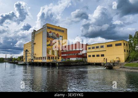 Vecchi edifici di fabbrica di mattoni gialli e rossi accanto all'acqua ferma con un cielo nuvoloso Foto Stock