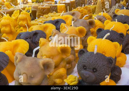 Collezione di candele di cera d'api fatte a mano a forma di orsi, angeli e figure decorative esposte in un tradizionale bancone di mercato artigianale. Foto Stock