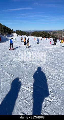 Gli sciatori sciano su una pista innevata presso la stazione sciistica di Valdelinares con il sole in inverno. Valdelinares, Teruel, Spagna - 19 gennaio 2025. Foto Stock