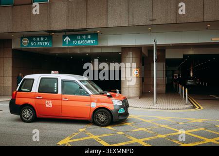 Taxi rosso che passa davanti agli uffici vicino a Harbour City Foto Stock