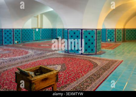 Interno della sala di preghiera della Moschea dello Scià a Isfahan, Iran. La foto presenta grandi tappeti rossi su un pavimento piastrellato turchese e pilastri ottagonali wi Foto Stock