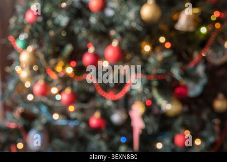 Vista orizzontale ravvicinata di un albero di Natale decorato con ornamenti come stelle, campane e biglie rosse e dorate. Fata calda e luminosa Foto Stock