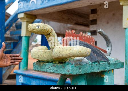 Mano che si protende verso una scultura di serpente dipinta su un altare posuban, Gomoa Otsew, Ghana Foto Stock