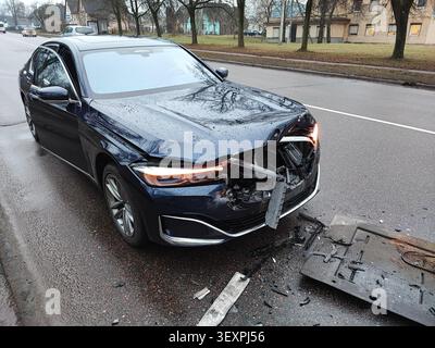 Scena dell'incidente stradale urbano: Vettura di lusso danneggiata dopo una collisione in piedi sulla carreggiata tra detriti Foto Stock