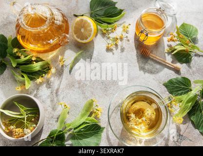 Tè al tiglio con fiori di lime, limone e miele su una superficie grigia Foto Stock