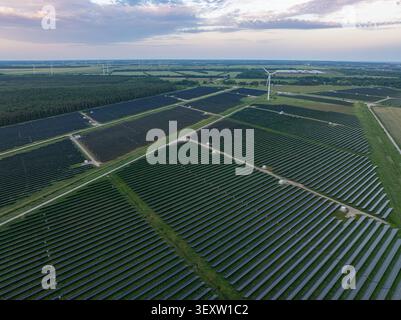 Vista aerea di un grande parco solare e turbine eoliche all'alba vicino a Pope, comune di Ventspils, Lettonia Foto Stock