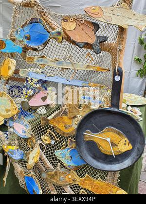 Tallinn, Estonia - 7 luglio 2022: Decorazioni di pesce in ceramica fatte a mano e orologio a padella esposti sulla rete da pesca al mercato, Tallinn Medieval Days Foto Stock