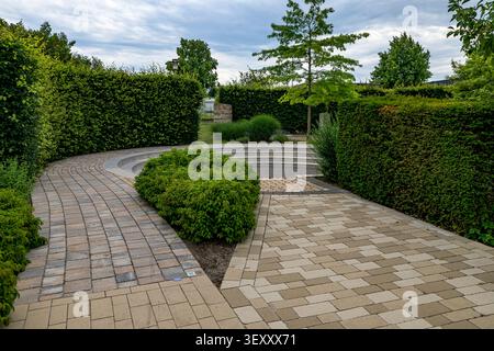 Vista ad angolo alto di vialetti lastricati in pietra che si intersecano e di siepi verdi curate in un parco o giardino moderno meravigliosamente progettato. Foto Stock
