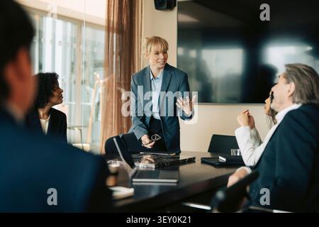 Manager donna che condivide idee con il team durante la riunione in ufficio Foto Stock