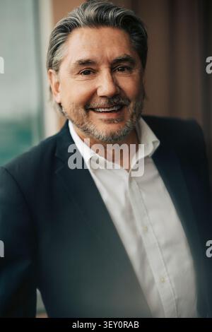 Ritratto di un uomo d'affari sorridente in tuta nera in ufficio Foto Stock