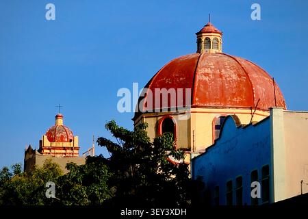 Cupole gemelle rosse della chiesa contro il cielo blu (Oaxaca de Juarez, Messico) Foto Stock