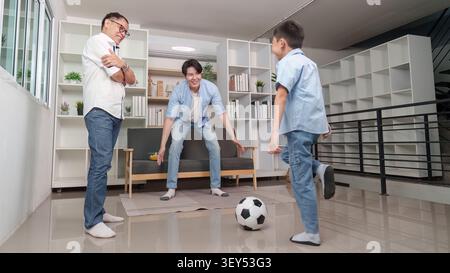Famiglia asiatica multigenerazionale che gioca a calcio insieme nel soggiorno Foto Stock