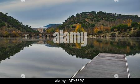 Vista autunnale dall'area ricreativa di la Depuradora sul fiume Alberche con sullo sfondo il ponte di San Juan, vicino a Pelayos de la presa, Madrid, Spagna Foto Stock