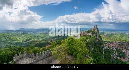 Vista panoramica della torre Guaita sulla scogliera rocciosa del Monte Titano circondata da dolci colline sotto un cielo spettacolare. Repubblica di San Marino Foto Stock