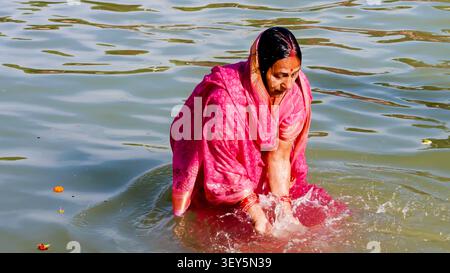 Donna che si immerge nel fiume Santo durante la cerimonia di purificazione religiosa indù Foto Stock