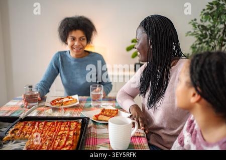 La famiglia si diverte con la pizza e chiacchiera insieme a casa Foto Stock