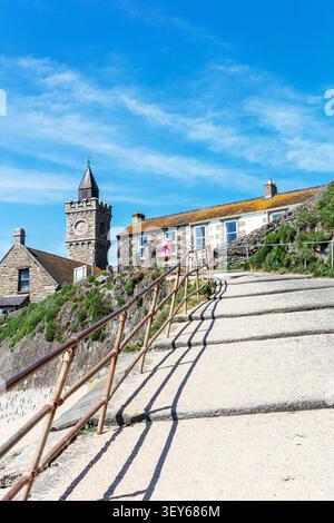 Un ripido sentiero costiero a Porthleven, Cornovaglia, che conduce in salita tra ringhiere metalliche e terreno roccioso con vegetazione verde. Nella parte superiore si trova un sto Foto Stock