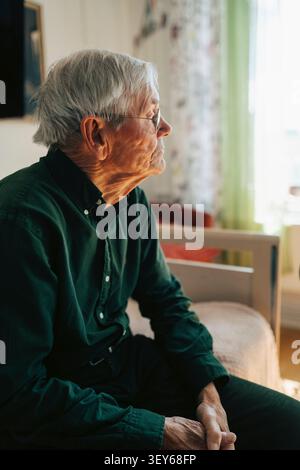 Un anziano premuroso seduto da solo sul letto nella casa di riposo Foto Stock