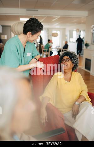 Infermiera che condivide momenti felici con una donna anziana in pensione Foto Stock
