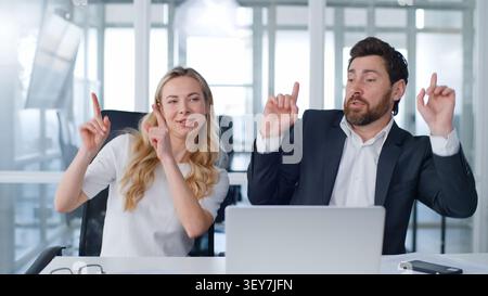 Due partner d'affari che ballano al tavolo dell'ufficio uomo d'affari caucasico di mezza età con una donna d'affari ballano insieme in un computer portatile aziendale Foto Stock