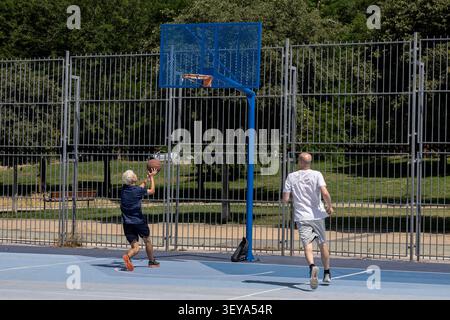 Uomini che giocano a basket su un campo all'aperto Foto Stock