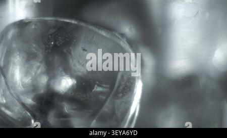 Macro shot a cubetti di ghiaccio che mostra la consistenza dell'acqua congelata, la superficie fredda dei cristalli e i riflessi astratti dell'argento Foto Stock