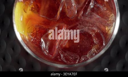 Cocktail Negroni con cubetti di ghiaccio e buccia d'arancia da vicino, gustando un rinfrescante aperitivo Foto Stock